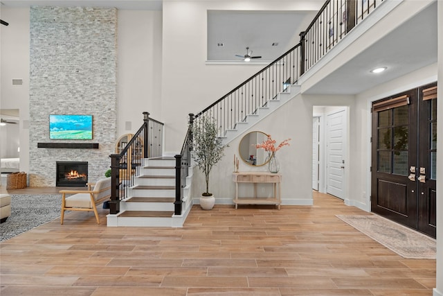 foyer entrance featuring ceiling fan, a fireplace, and a towering ceiling