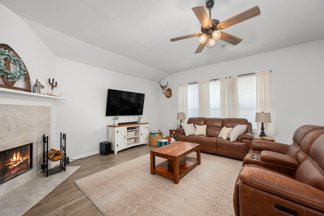 living room featuring a tile fireplace, ceiling fan, wood-type flooring, and lofted ceiling