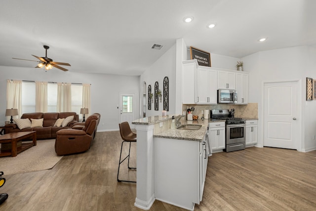 kitchen featuring white cabinetry, a kitchen bar, kitchen peninsula, and stainless steel appliances