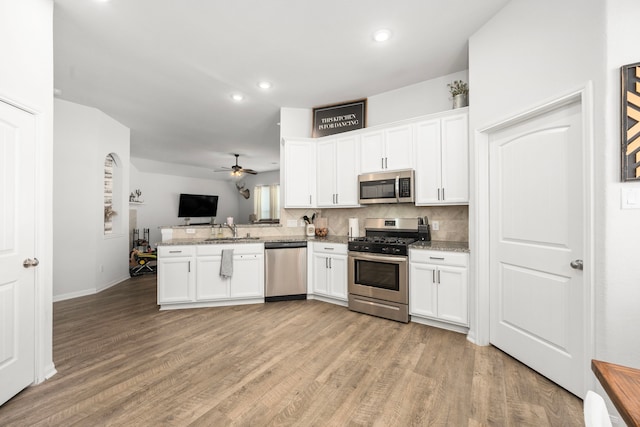 kitchen featuring kitchen peninsula, white cabinetry, stainless steel appliances, and light wood-type flooring