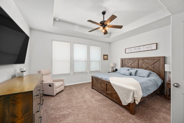 carpeted bedroom featuring a tray ceiling and ceiling fan