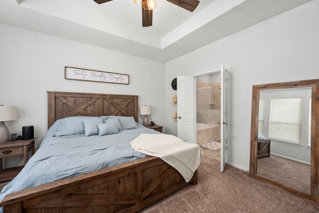 carpeted bedroom featuring ceiling fan, a raised ceiling, and ensuite bath