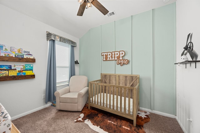 carpeted bedroom featuring vaulted ceiling, a nursery area, and ceiling fan