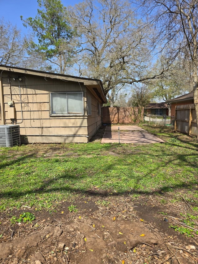 view of home's exterior featuring a patio area, central AC, fence, and a lawn