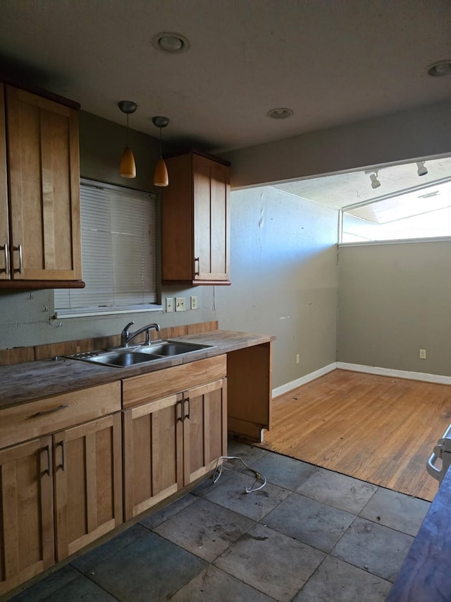 kitchen with baseboards, wood finished floors, a sink, and decorative light fixtures