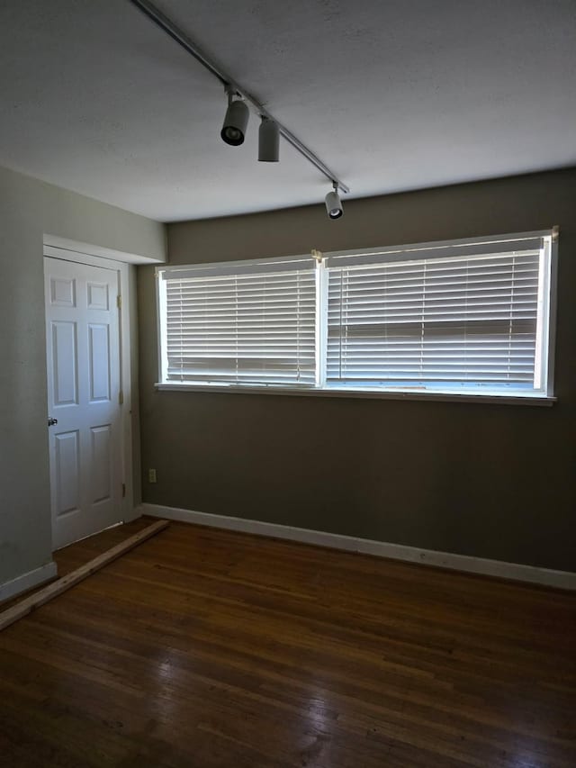 unfurnished room featuring a wealth of natural light, baseboards, and wood finished floors