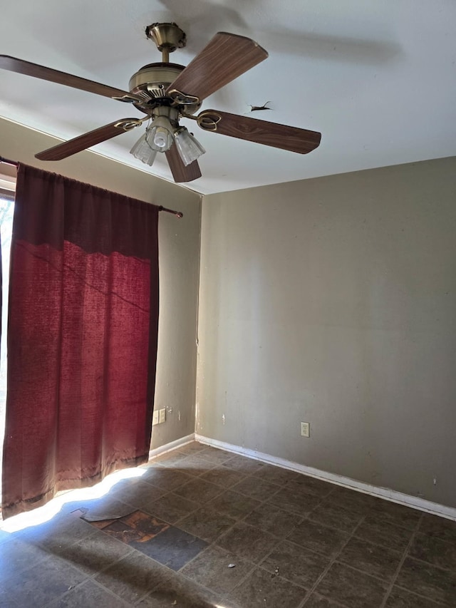 spare room with stone finish floor, ceiling fan, and baseboards