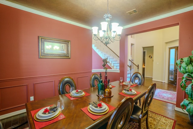 dining space featuring ornamental molding, a textured ceiling, a chandelier, and wood-type flooring