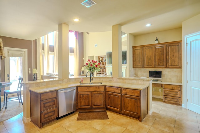 kitchen with kitchen peninsula, stainless steel dishwasher, light tile patterned floors, tasteful backsplash, and sink