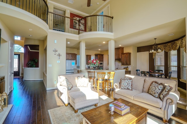 living room with a high ceiling, dark wood-type flooring, and a notable chandelier