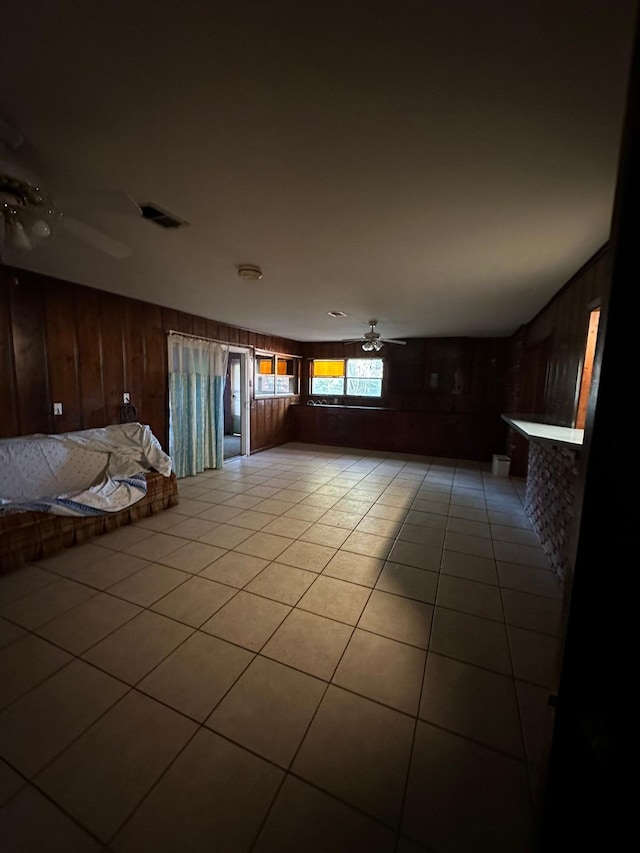 tiled empty room featuring wooden walls and ceiling fan