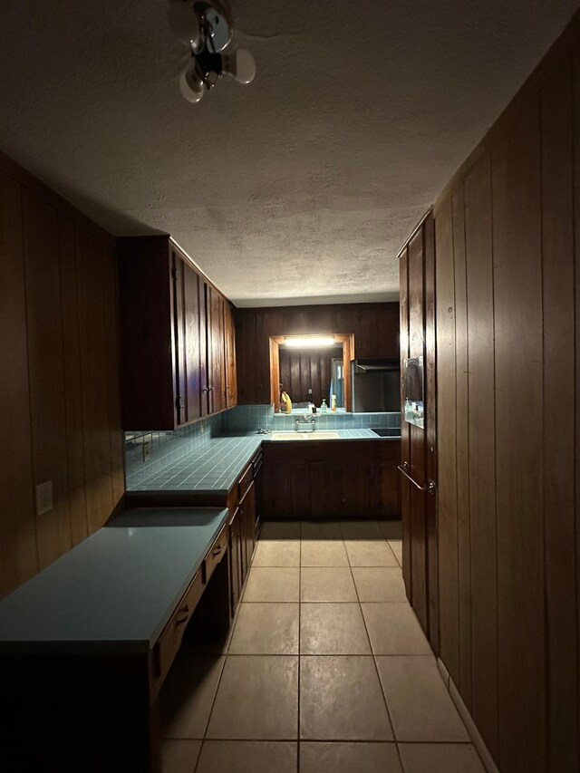 kitchen with kitchen peninsula, a textured ceiling, and wood walls