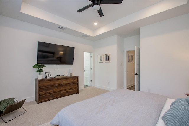 carpeted bedroom featuring ceiling fan and a tray ceiling