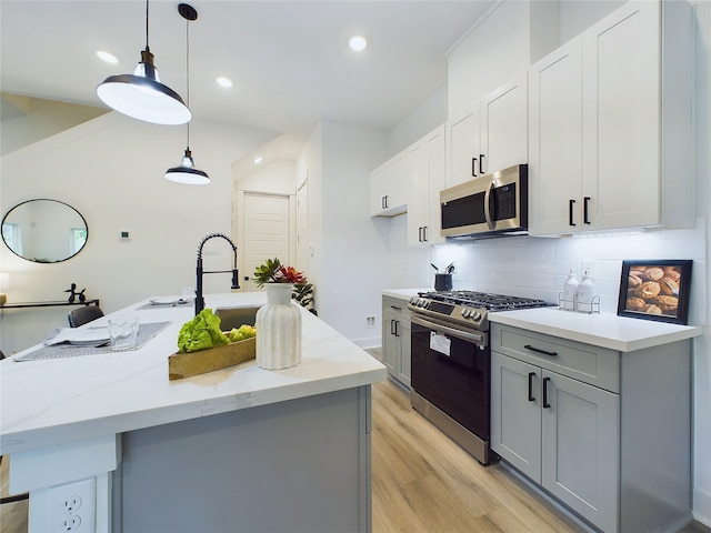 kitchen with appliances with stainless steel finishes, decorative light fixtures, light stone counters, and a center island with sink