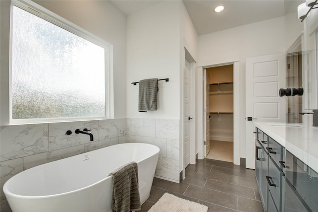 bathroom with tile patterned flooring, plenty of natural light, a tub, and vanity