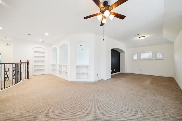 unfurnished room featuring light carpet, built in shelves, and ceiling fan