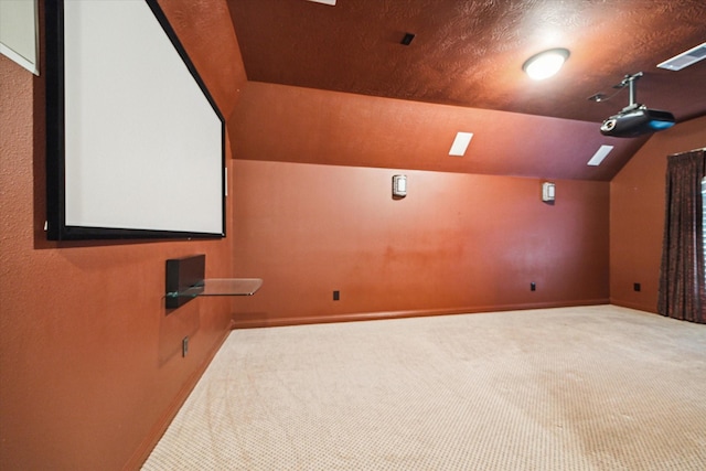 carpeted cinema room with a textured ceiling and vaulted ceiling