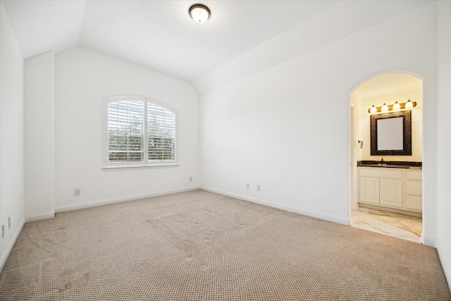 carpeted spare room with lofted ceiling and sink