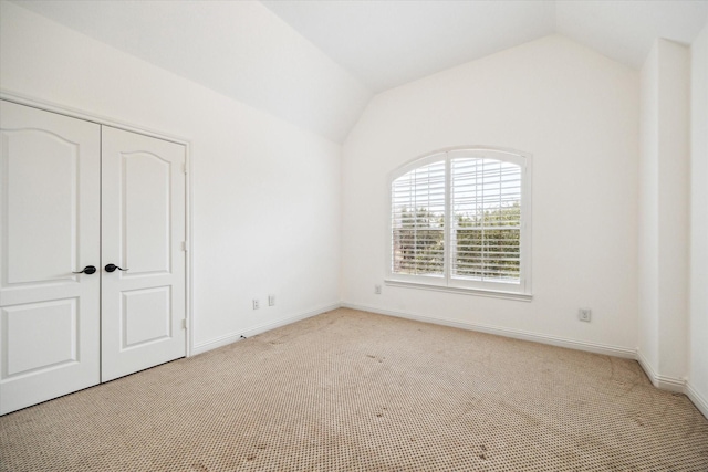 unfurnished bedroom featuring lofted ceiling, light carpet, and a closet