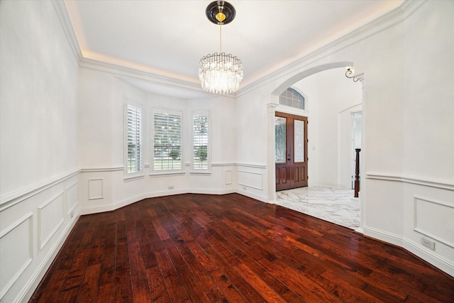 empty room featuring ornamental molding, french doors, wood-type flooring, and an inviting chandelier