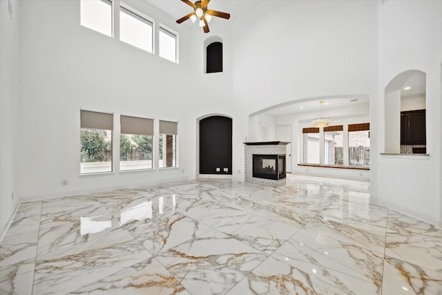 unfurnished living room with a multi sided fireplace, a towering ceiling, and a healthy amount of sunlight