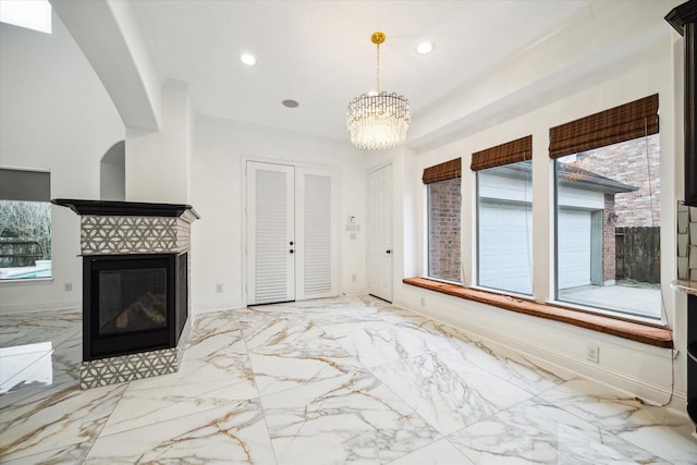 unfurnished living room featuring a tile fireplace, french doors, and a notable chandelier