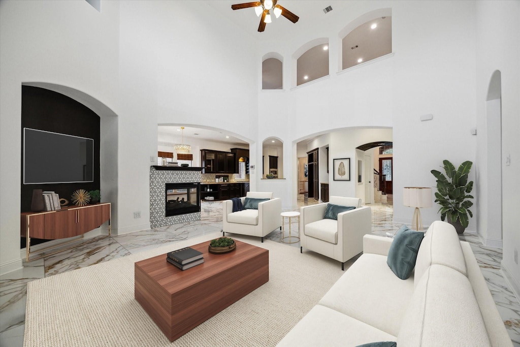 living room with arched walkways, marble finish floor, and a ceiling fan