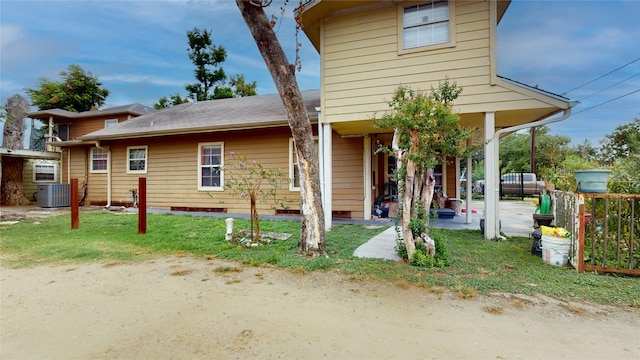 view of front of house with cooling unit and a front lawn