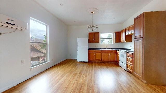 kitchen with a wall mounted air conditioner, white appliances, sink, decorative light fixtures, and a chandelier