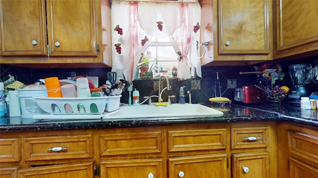 kitchen featuring backsplash, sink, and dark stone counters