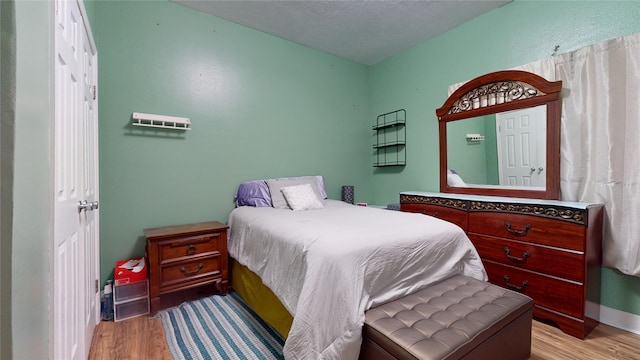 bedroom featuring a textured ceiling and light hardwood / wood-style flooring