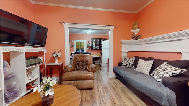 living room with light wood-type flooring, ceiling fan, and ornamental molding