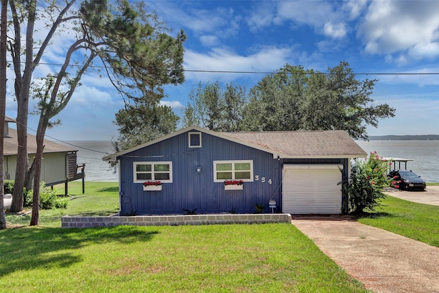 view of front of property featuring a front lawn, a garage, and a water view