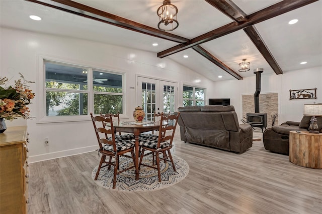 dining area featuring a wood stove, light hardwood / wood-style flooring, french doors, and vaulted ceiling with beams