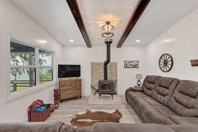 living room with light hardwood / wood-style floors, a wood stove, and beamed ceiling