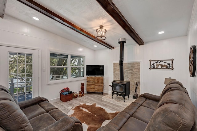 living room with vaulted ceiling with beams, light wood-type flooring, a chandelier, and a wood stove