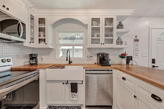 kitchen with tasteful backsplash, appliances with stainless steel finishes, white cabinets, and butcher block countertops