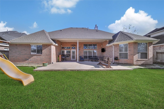 back of house featuring a yard, a playground, and a patio area