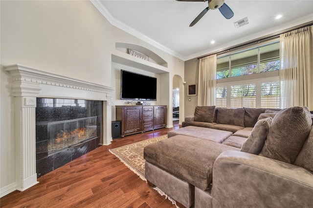 living room featuring hardwood / wood-style floors, built in shelves, ceiling fan, ornamental molding, and a tiled fireplace