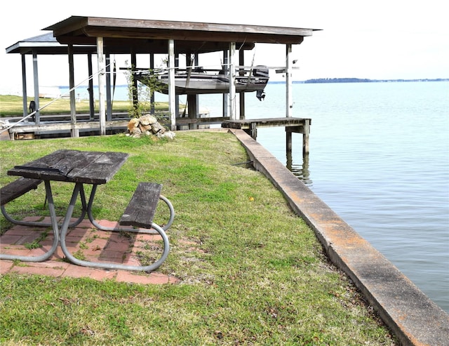 dock area with a water view, a lawn, and boat lift