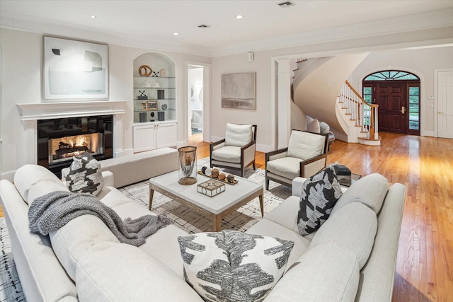 living room featuring crown molding, built in features, and hardwood / wood-style flooring