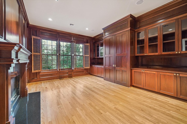 unfurnished living room with a fireplace, wooden walls, and light hardwood / wood-style floors