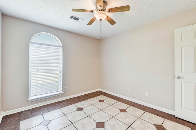 spare room featuring ceiling fan, light tile patterned floors, and a textured ceiling