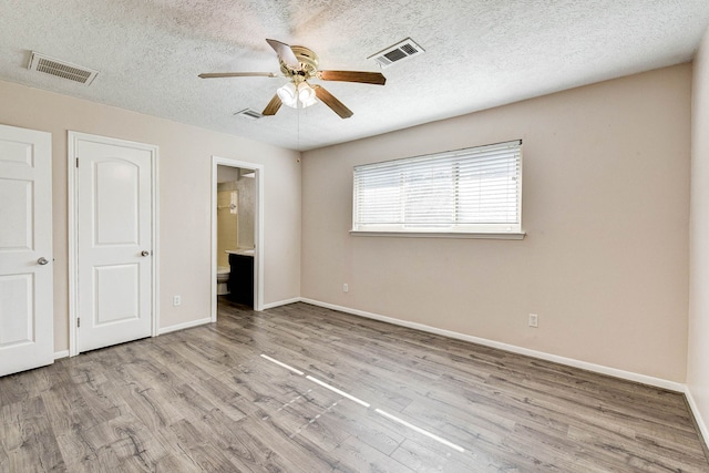 unfurnished bedroom with a textured ceiling, ensuite bathroom, ceiling fan, and light hardwood / wood-style floors