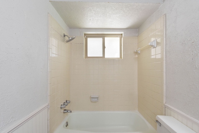 bathroom with tiled shower / bath combo, toilet, and a textured ceiling