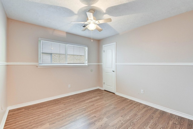 spare room featuring ceiling fan, light wood-type flooring, and a textured ceiling