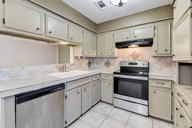 kitchen featuring light tile patterned flooring, a textured ceiling, stainless steel appliances, and sink