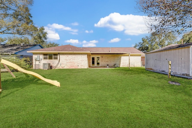 back of property with a playground, central air condition unit, and a yard