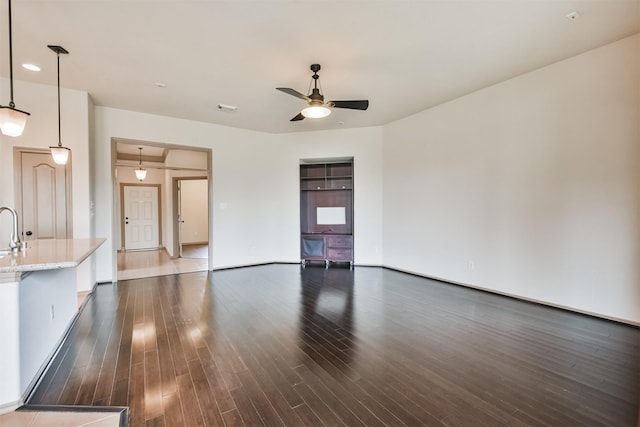 unfurnished living room featuring dark wood-type flooring and ceiling fan