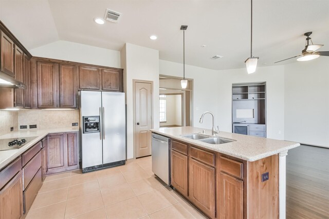 kitchen with sink, tasteful backsplash, decorative light fixtures, stainless steel appliances, and a kitchen island with sink